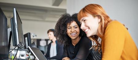 Two women smiling at computer