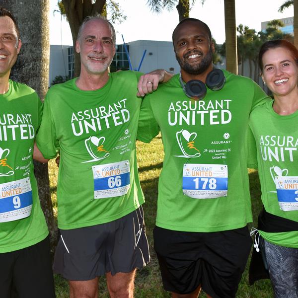 Image of four Assurant employees smiling after completing 5K charity race